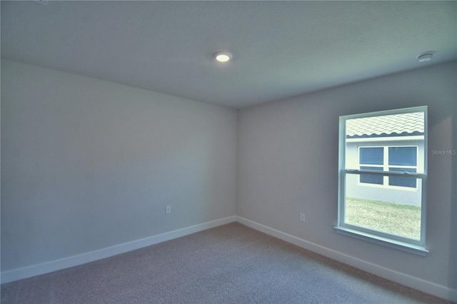 empty room featuring plenty of natural light, baseboards, and light colored carpet