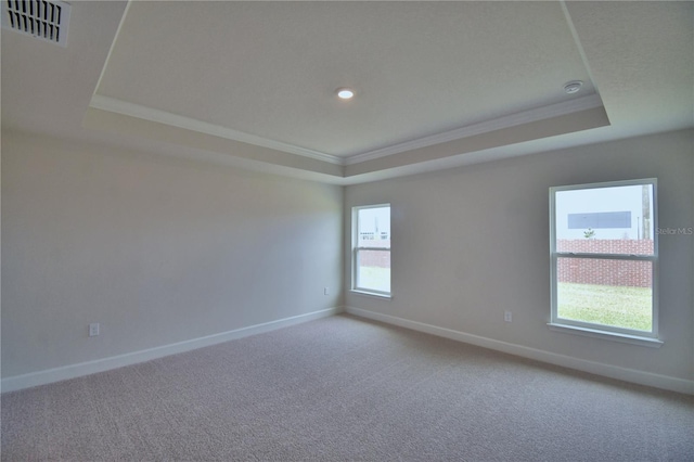 empty room with baseboards, a tray ceiling, carpet, and visible vents
