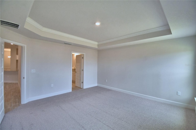 carpeted spare room featuring baseboards, visible vents, crown molding, and a raised ceiling