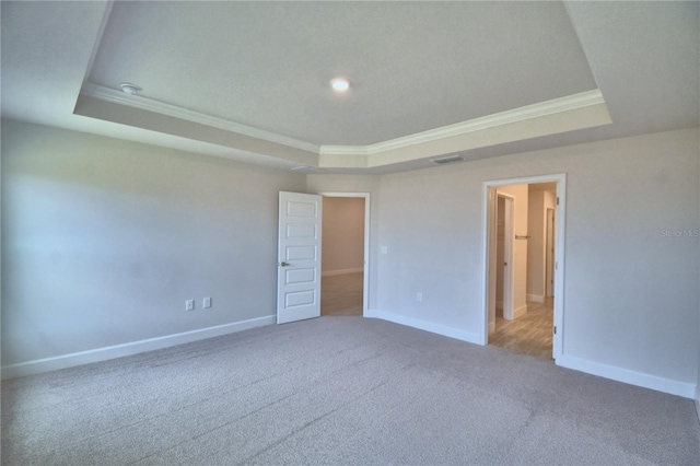 unfurnished bedroom with carpet flooring, a raised ceiling, baseboards, visible vents, and ornamental molding
