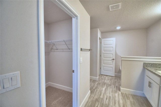 interior space featuring light wood finished floors, baseboards, visible vents, and a textured ceiling