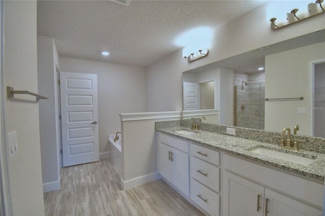full bath with a sink, a garden tub, a shower stall, and wood finished floors