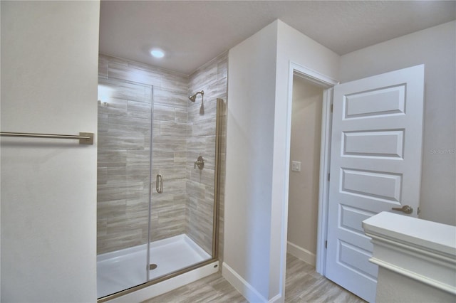 bathroom featuring baseboards, wood finished floors, and a shower stall