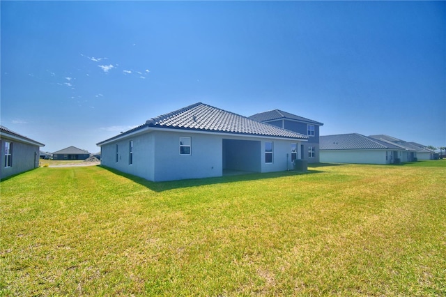 rear view of house with a tile roof, stucco siding, central air condition unit, and a lawn