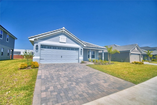 single story home featuring a tile roof, a front yard, decorative driveway, and a garage