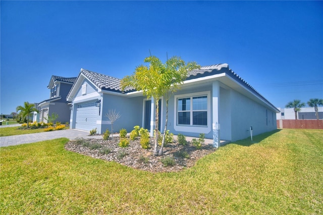 ranch-style house with a tile roof, decorative driveway, a front yard, and stucco siding