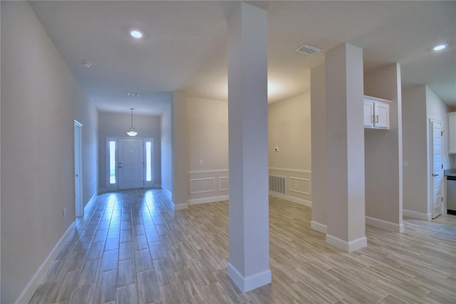 foyer entrance featuring a decorative wall, visible vents, recessed lighting, and light wood finished floors