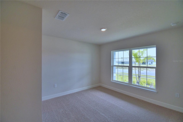 empty room featuring baseboards, visible vents, and light carpet