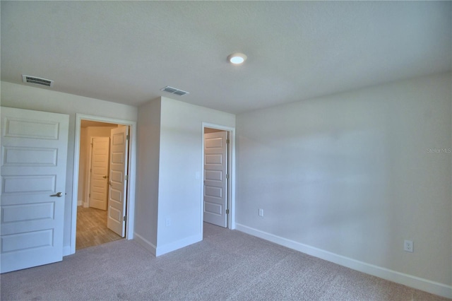 unfurnished bedroom featuring baseboards, carpet flooring, and visible vents