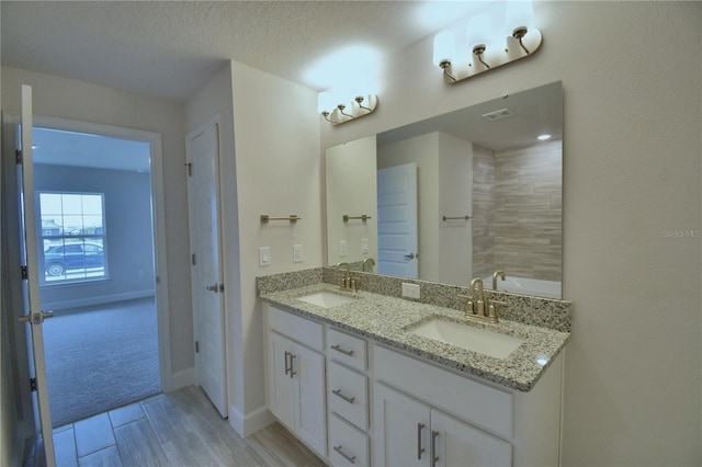 bathroom with double vanity, a sink, baseboards, and wood finished floors