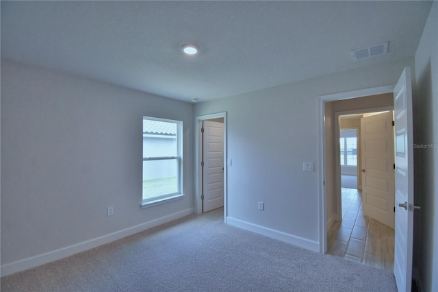 unfurnished bedroom featuring baseboards, visible vents, and light carpet