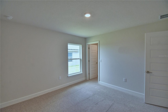 spare room featuring light carpet, baseboards, and visible vents