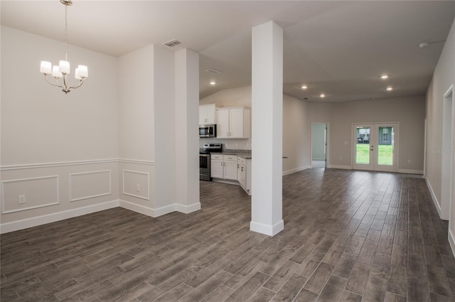 unfurnished living room featuring a chandelier, french doors, dark wood-type flooring, and vaulted ceiling