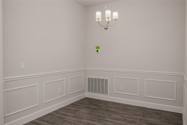 empty room with dark hardwood / wood-style floors and a notable chandelier