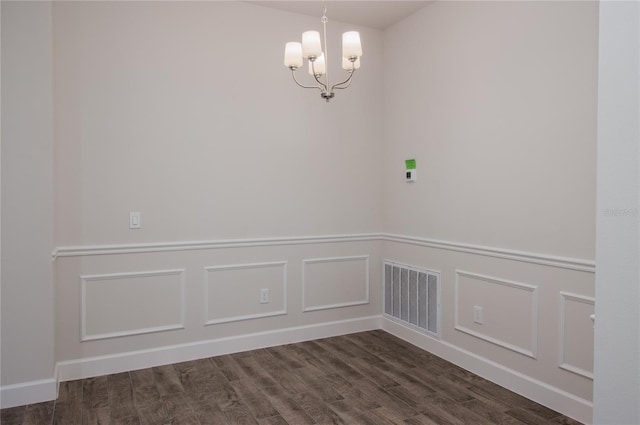 spare room with a notable chandelier and dark hardwood / wood-style flooring