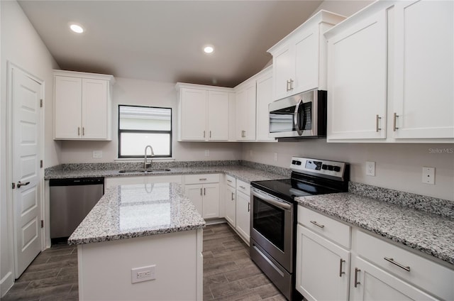 kitchen with white cabinets, appliances with stainless steel finishes, sink, and light stone counters