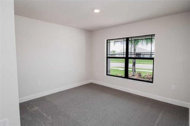 unfurnished room featuring dark colored carpet