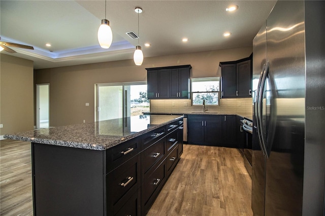 kitchen with pendant lighting, plenty of natural light, a kitchen island, and appliances with stainless steel finishes