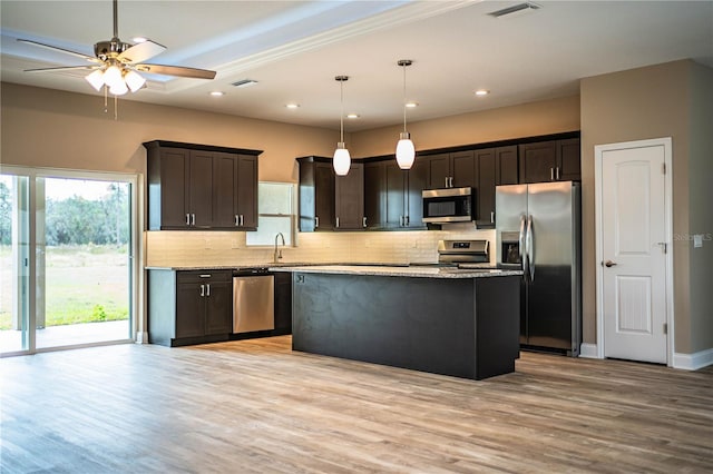 kitchen with pendant lighting, a center island, stainless steel appliances, and light hardwood / wood-style flooring