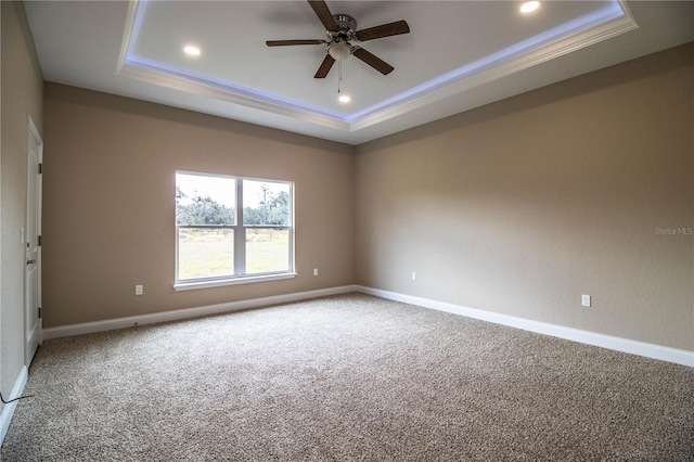 carpeted spare room with a tray ceiling and ceiling fan