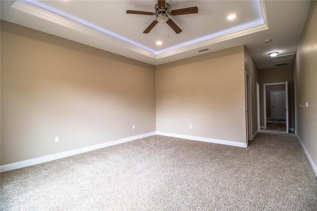 carpeted empty room with a raised ceiling and ceiling fan