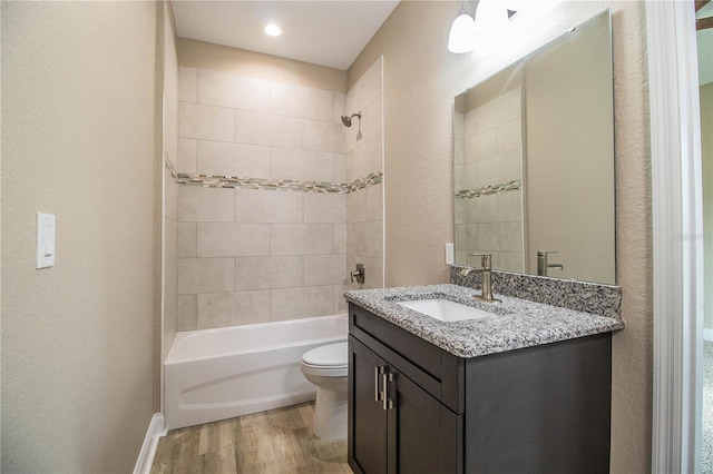 full bathroom with vanity, toilet, tiled shower / bath, and hardwood / wood-style flooring