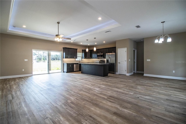 kitchen featuring appliances with stainless steel finishes, dark hardwood / wood-style flooring, a raised ceiling, pendant lighting, and a kitchen island