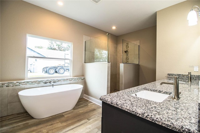 bathroom with plus walk in shower, wood-type flooring, vanity, and tile walls