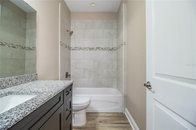 full bathroom featuring tiled shower / bath, hardwood / wood-style floors, vanity, and toilet