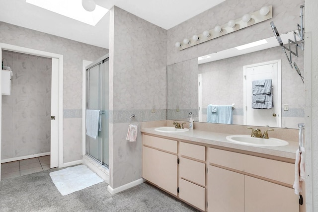 bathroom with vanity, a skylight, and a shower with shower door