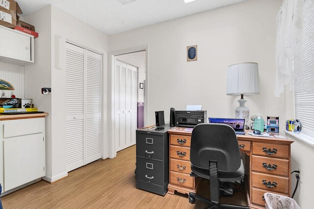 office space featuring a textured ceiling and light wood-type flooring