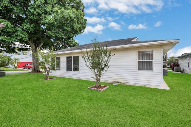 rear view of property with central AC and a yard