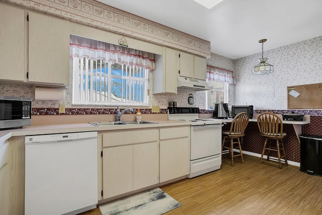 kitchen featuring a healthy amount of sunlight, sink, pendant lighting, and white appliances