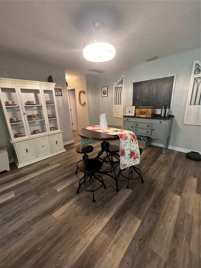 dining area with dark wood-type flooring and a textured ceiling