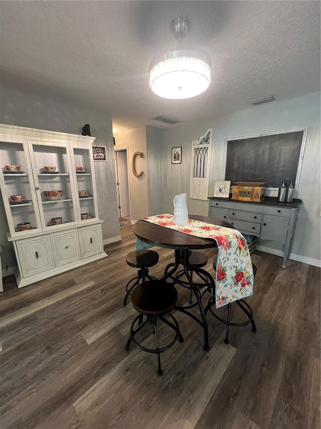 dining space with a textured ceiling and dark hardwood / wood-style flooring