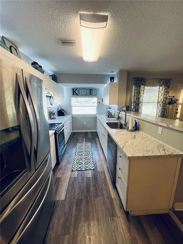 kitchen featuring appliances with stainless steel finishes, sink, plenty of natural light, and dark hardwood / wood-style flooring