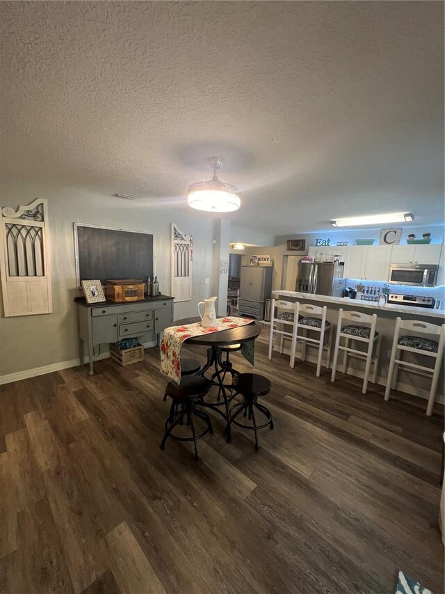 dining room featuring a textured ceiling and dark hardwood / wood-style flooring