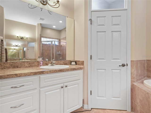 bathroom with tiled bath, vanity, and tile flooring