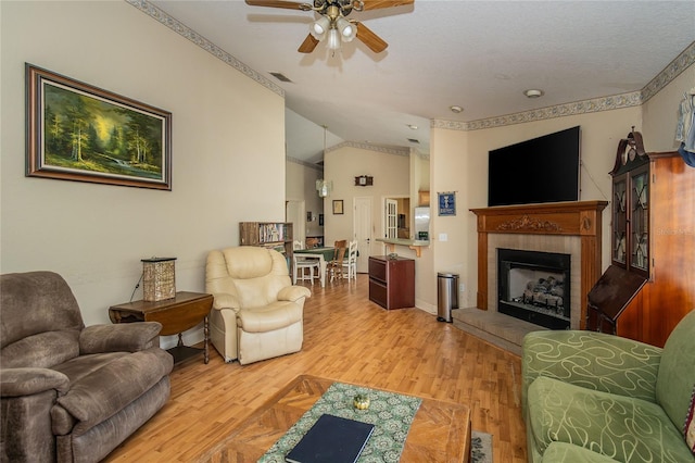 living room featuring hardwood / wood-style flooring, a tile fireplace, ceiling fan, and vaulted ceiling