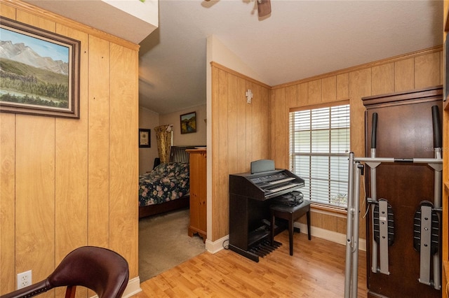 office featuring light hardwood / wood-style floors, wooden walls, ceiling fan, and vaulted ceiling