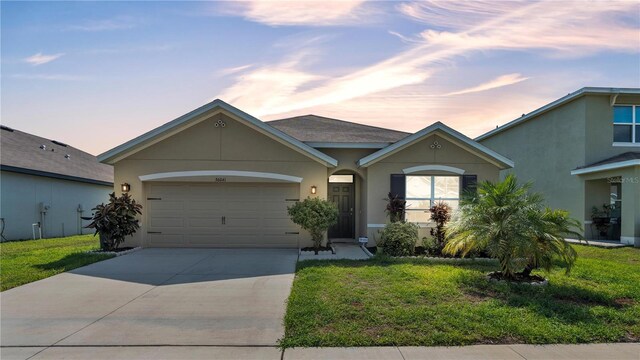 ranch-style house featuring a garage and a yard