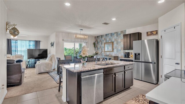 kitchen featuring a kitchen island with sink, appliances with stainless steel finishes, sink, light tile floors, and pendant lighting