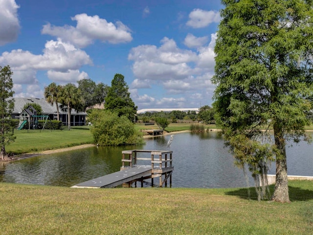 dock area featuring a playground, a water view, and a yard