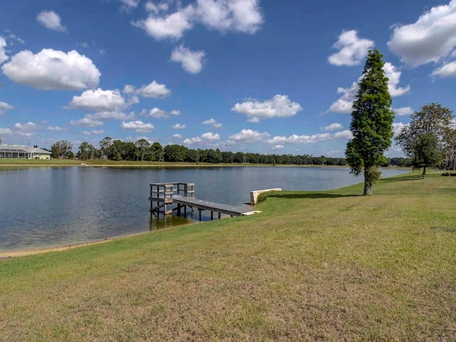 view of dock with a lawn and a water view