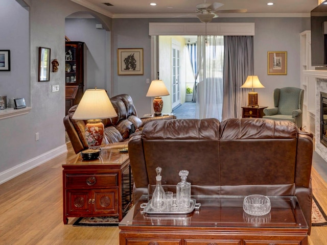 living room with a premium fireplace, ceiling fan, crown molding, and hardwood / wood-style flooring