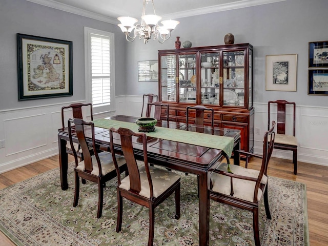 dining room featuring light hardwood / wood-style floors, ornamental molding, and an inviting chandelier