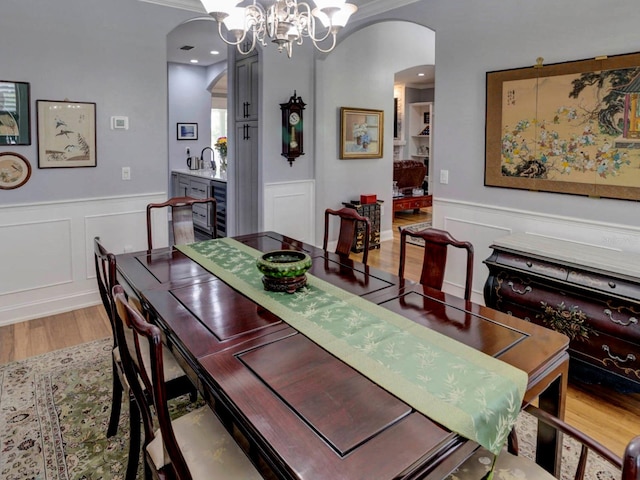 dining space featuring sink, beverage cooler, a chandelier, and wood-type flooring