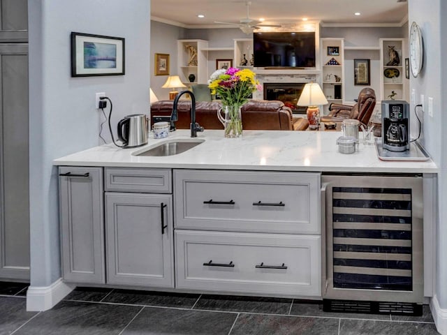 bar with beverage cooler, crown molding, light stone counters, dark tile flooring, and sink