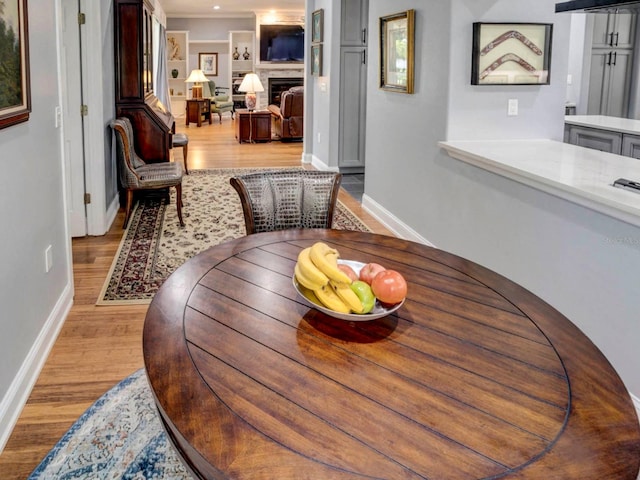 interior space featuring built in shelves, ornamental molding, and light hardwood / wood-style floors