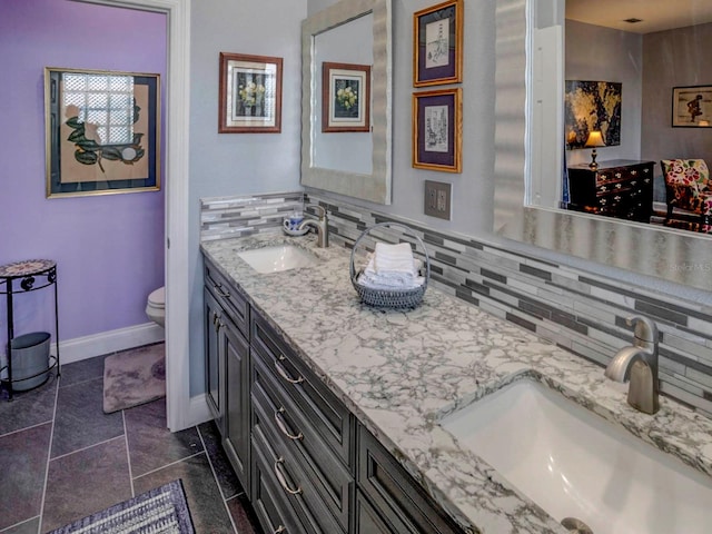 bathroom featuring double sink vanity, toilet, tasteful backsplash, and tile floors